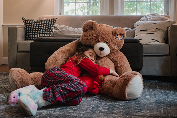 An image a child cuddling a 4-foot Big Hunka Love Bear