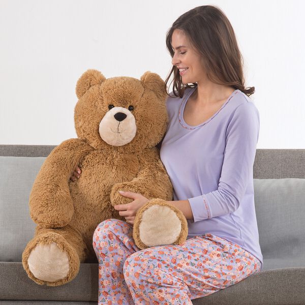 3' Hunka Love Bear - Seated golden brown bear with a female model in lavender pajamas on a sofa image number 0