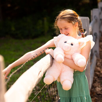 18" Oh So Soft Pig - Full length view of soft plush pink pig with model in outdoor setting