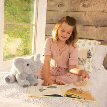 15" Classic Elephant - Three quarter view of seated gray plush elephant in a bedroom scene with a girl model