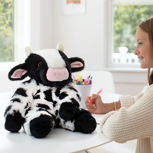18" Oh So Soft Cow - Black and white Holstein cow with pink nose and ears and a model in a living room scene
