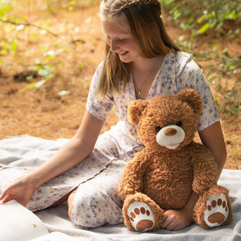 20" Bubba the Fuzzy Teddy Bear - Front view of seated almond brown bear with model in an outdoor scene