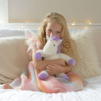 13" Unicorn Snuggle Pal - Seated front view of ivory unicorn weighted stuffed animal with model in bedroom scene