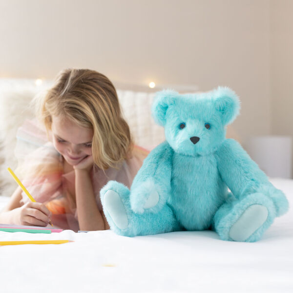 15" Blue Raspberry Lemonade Bear - Front view of jointed aqua blue bear with white paw pads in a bedroom scene with a model image number 1
