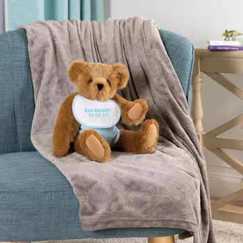 15" Baby Boy Bear - Seated jointed bear dressed in light blue with white dots fabric diaper and bib on a chair in a living room setting