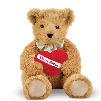 20" World's Softest Bear with Heart Pillow - 20" seated golden brown bear with brown eyes holding a red fleece pillow with white diagonal sash. Pillow is personalized with "I Love Sarah" in red lettering.